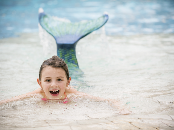 Mädchen schwimmt mit einer Meerjungfrauenflosse