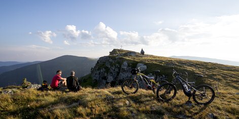 Rast beim Radfahren auf der Frauenalpe mit Gipfelkreuz im Hintergrund