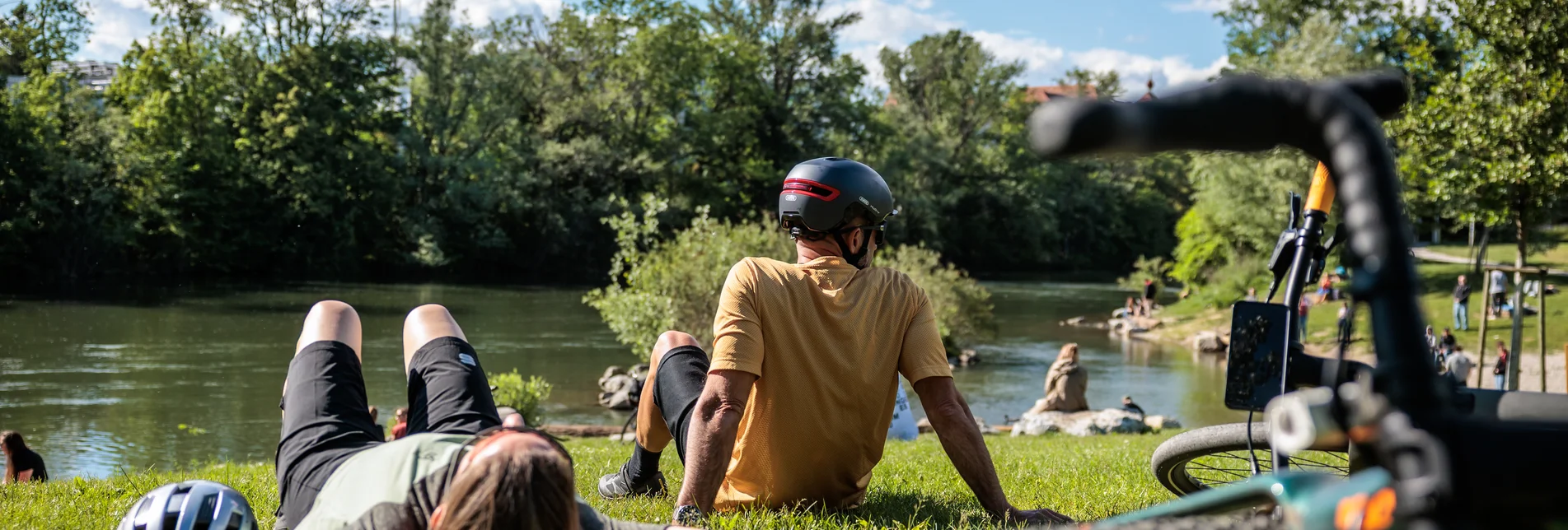 Radler liegen entspannt am Ufer der Mur