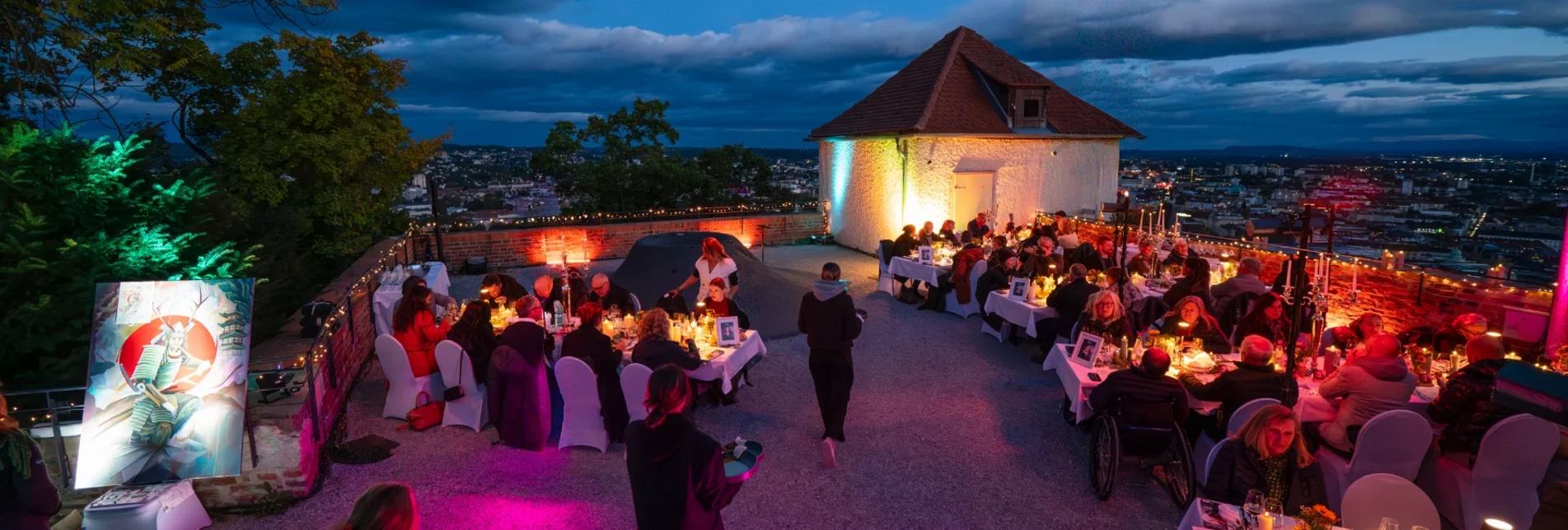 Gäste genießen das Abendessen beim Event Vollmund  am Schlossberg mit Blick auf Graz