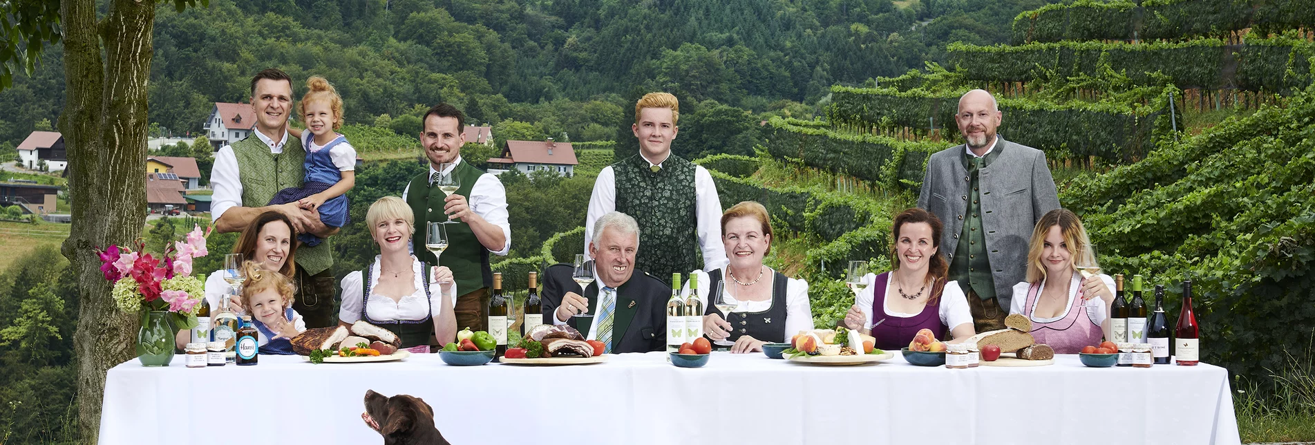 Familie Schneeberger sitzt an einer langen gedeckten Tafel | © Buschenschank Schneeberger