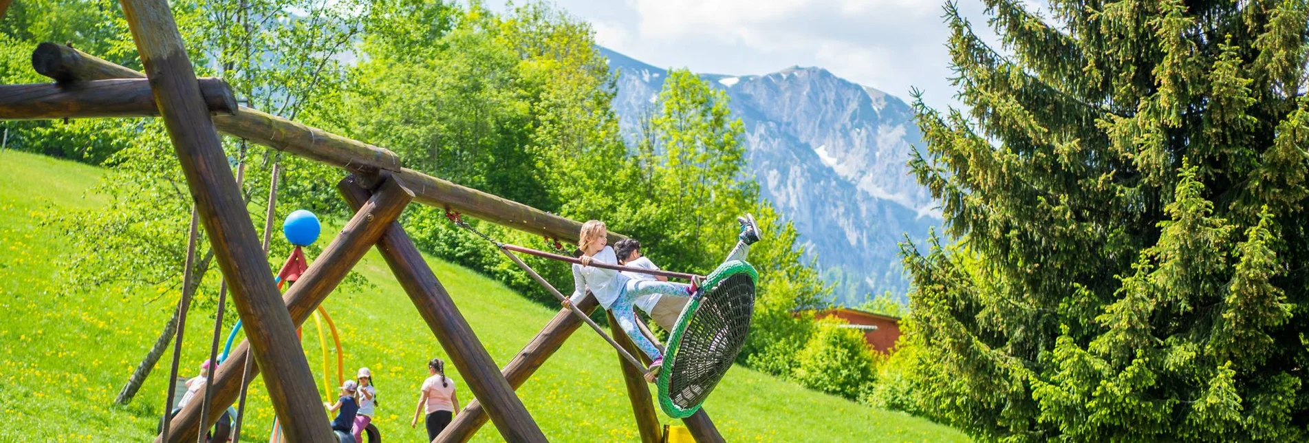 Ein Mädchen steht auf der Korbschaukel und will hoch hinaus