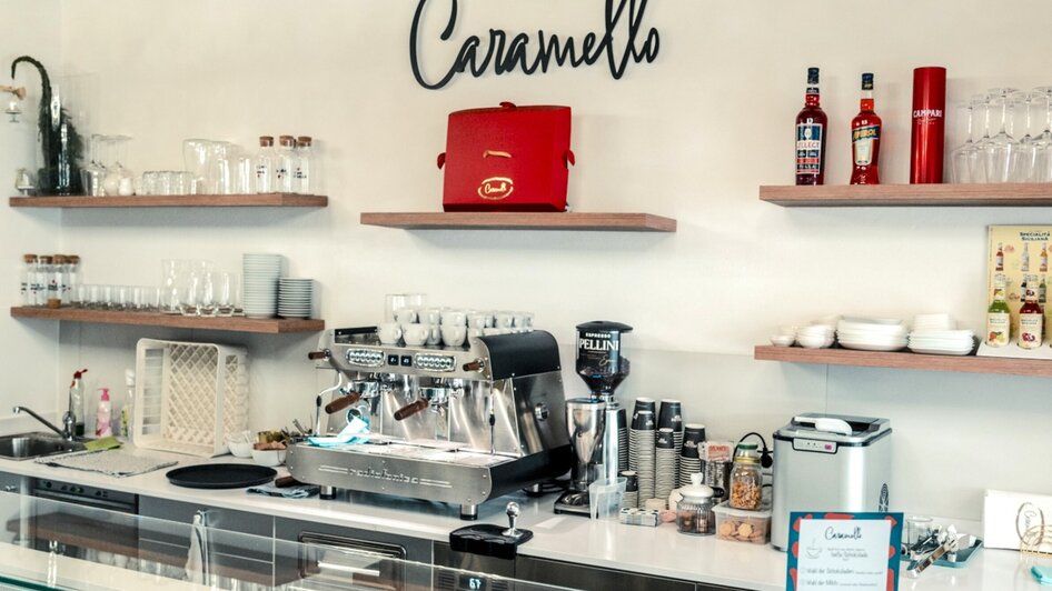 Vitrine eines Cafés mit Desserts und Kaffeemaschine.