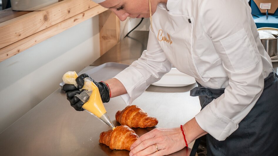 Eine Köchin dekoriert Croissants in einer modern gestalteten Küche.