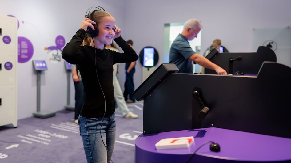 CoSA Jugendlicher  mit Kopfhörern im Museum | © Stellework Ein lächelnder Teenager trägt Kopfhörer und erkundet interaktive Displays im Museum. | © Stellework