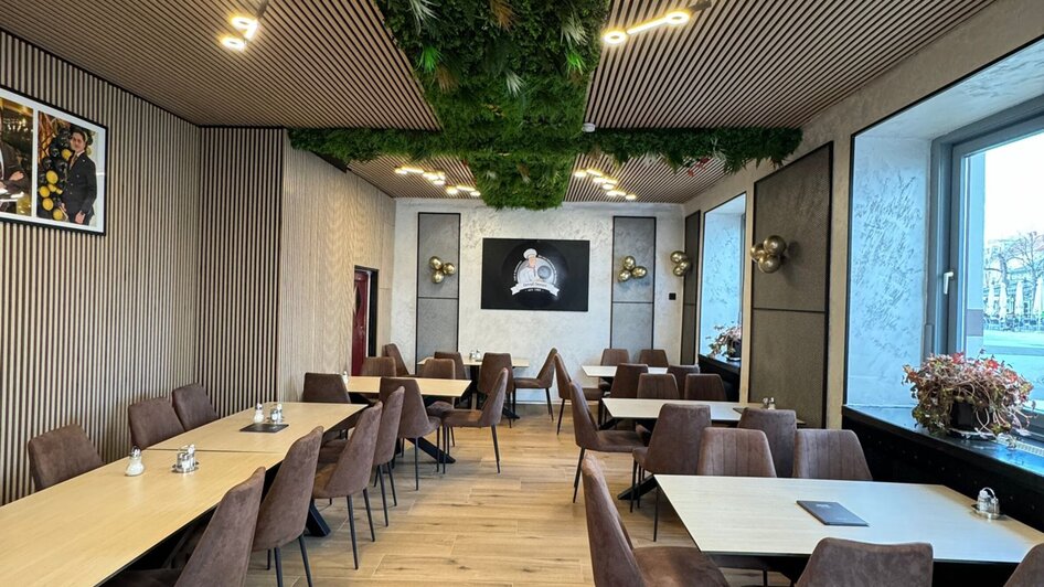Modernes Café-Restaurant mit Pflanzenwand und eleganten Tischen.