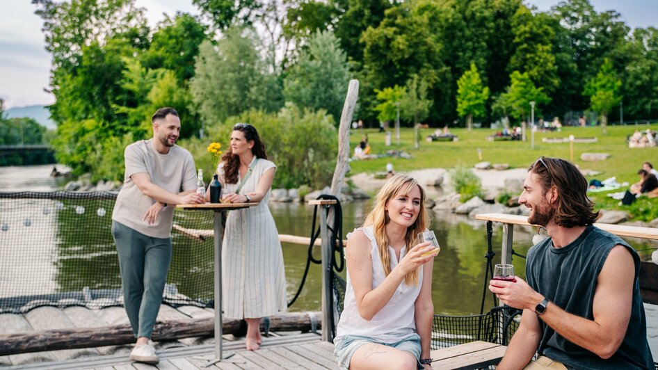 Freunde genießen Getränke auf einem Floß auf der Mur in Graz bei schönem Wetter. | © Graz Tourismus - Mias Photoart