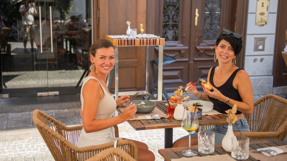 Zwei Frauen genießen ihr Essen im Freien im Lokal dreizehn by Gauster in Graz.