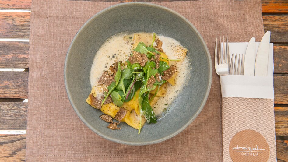Ein Gericht von dreizehn by Gauster mit Pasta, grünem Blattgemüse und Trüffeln.