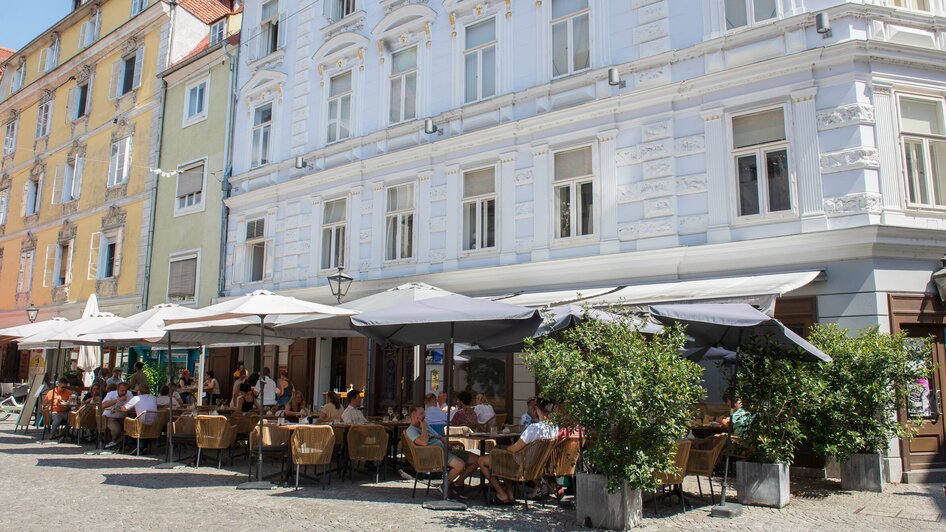 Besucher genießen das Essen im Gastgarten des Lokals dreizehn by Gauster in Graz.