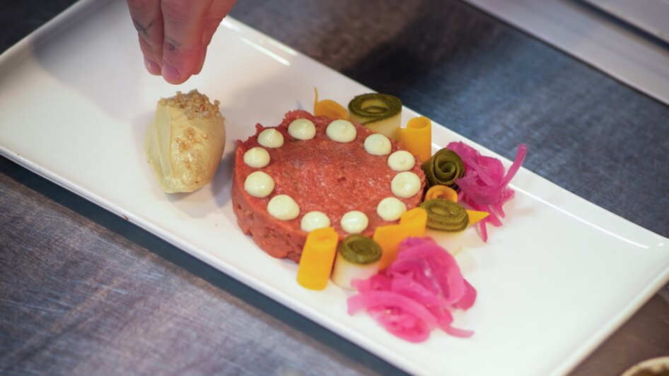 Ein kreatives Gericht mit farbigen Zutaten wird angerichtet.