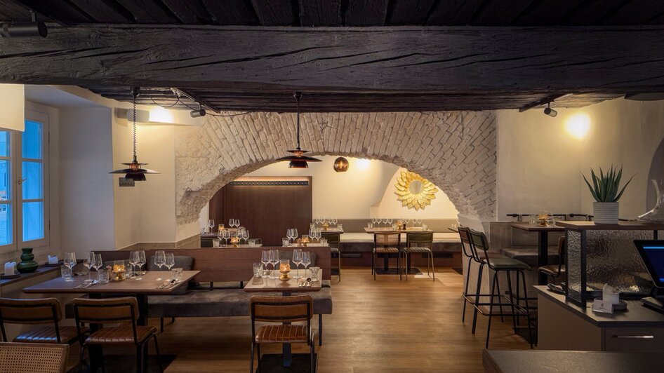 Modernes Restaurant mit Holzdecke und gedeckten Tischen.