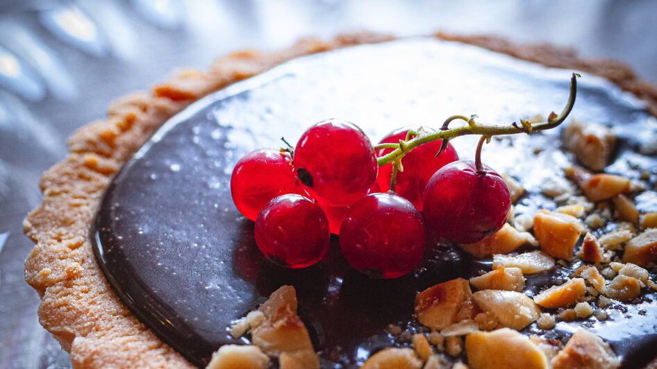Leckere Tarte mit Schokoladenfüllung, Nüssen und roten Ribiseln.