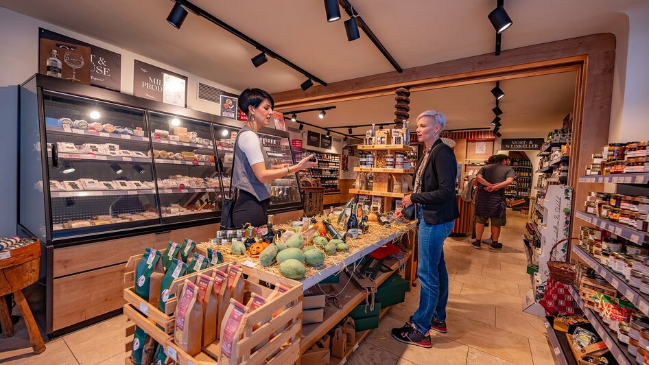 Kunde berät sich mit Verkäuferin im Feinkostladen in Graz.