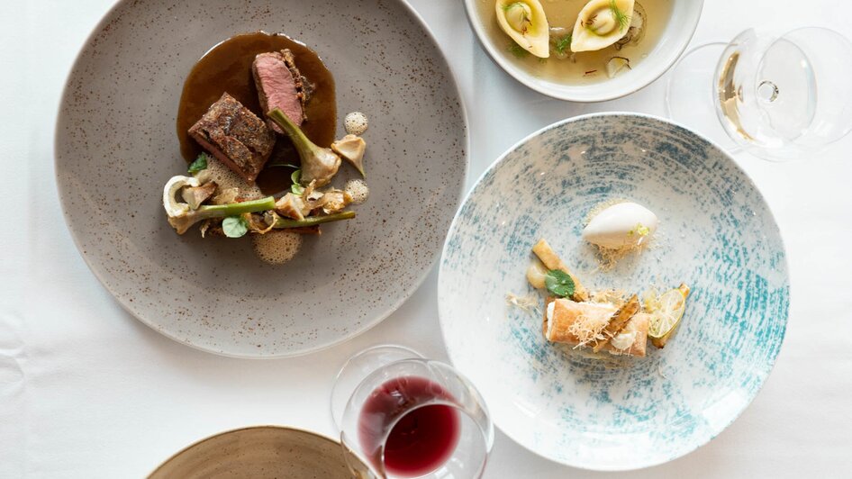 Verschiedene kunstvoll angerichtete Gerichte auf Tischen.