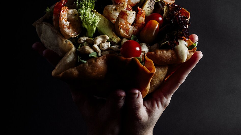 Große Schüssel mit Meeresfrüchten und Gemüse in Händen.