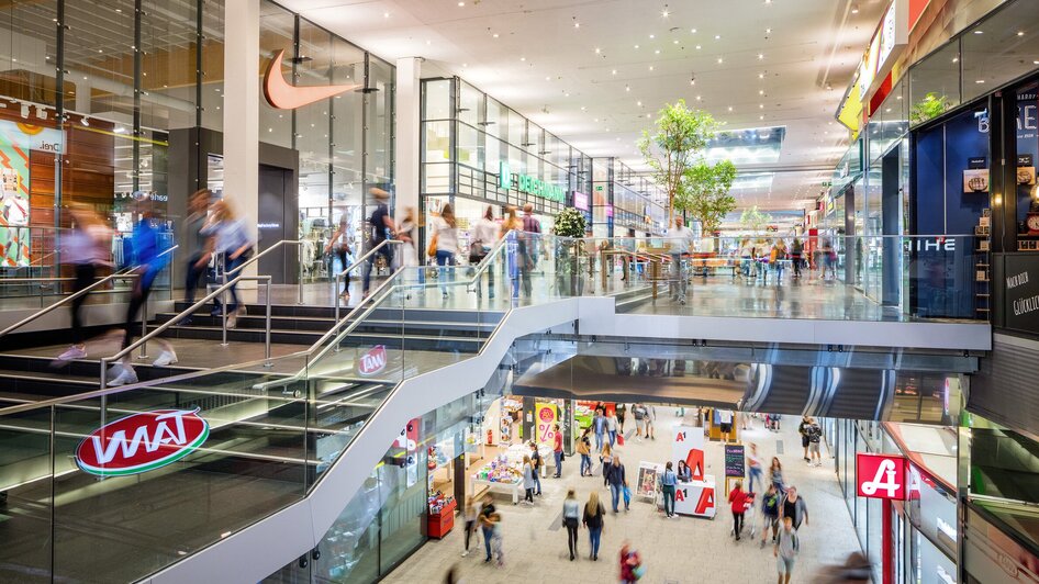 Im inneren eines Einkaufszentrums gehen viele Menschen umher.