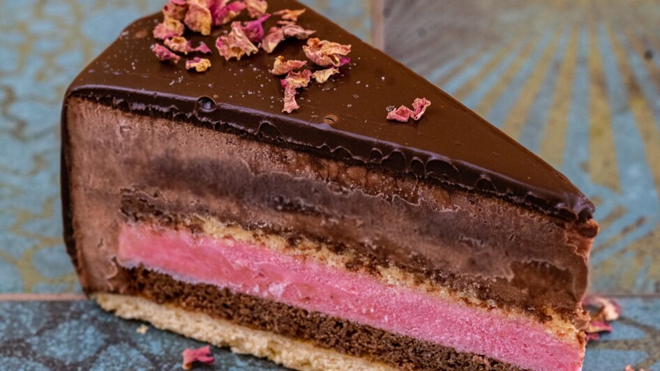 Schokoladige Torte mit rosa Schicht und Rosenblättern. | © Mona Ramsenthaler