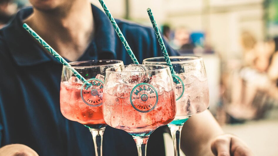 Ein fröhlicher Barkeeper serviert bunte Cocktails auf einem Tablett.