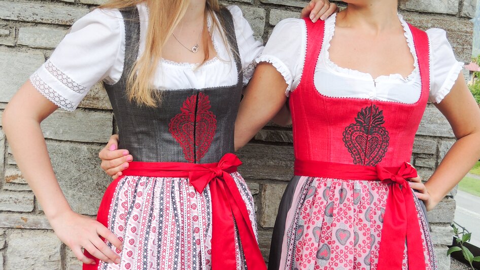 Zwei Frauen im roten dirndl mit besticktem Leib.