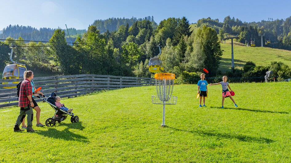 Disc-Golf Parcour am hauser Kaibling | René Eduard Perhab | © Hauser Kaibling@René Eduard Perhab Familie mit Kinderwagen und Kindern vor Disc-Golf Korb | © Hauser Kaibling@René Eduard Perhab