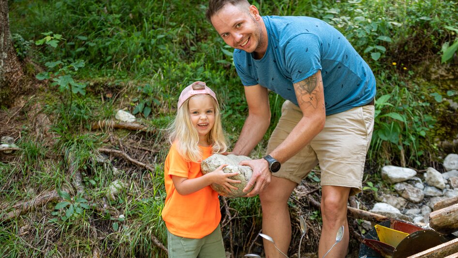 Vater hält gemeinsam mit Tochter großen Stein in der Hand  | © Lorenz Maser 