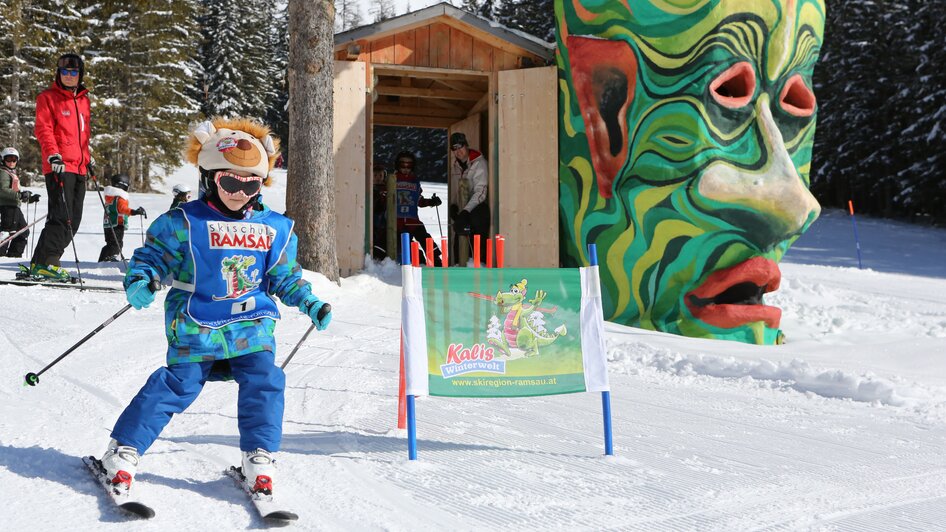 Kind am Skifahren mit kunstvollem Steinkopf im Hintergrund. | © Hans-Peter Steiner