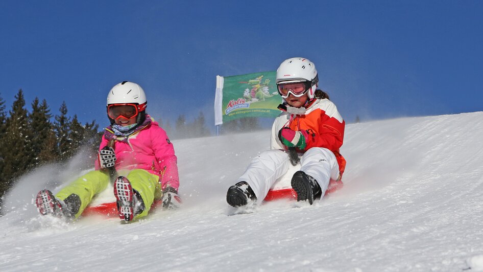 Zwei Kinder auf Zipfelbobs. 